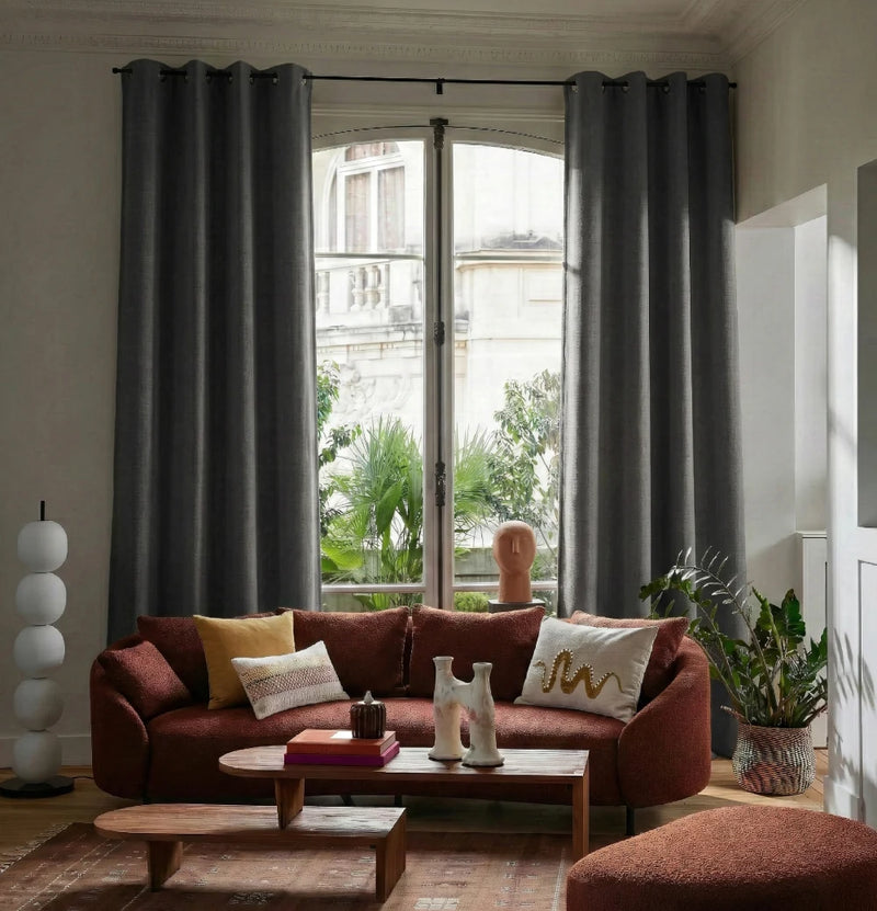 Salon haussmannien avec rideaux sur mesure Kurtens gris anthracite occultants thermiques et phoniques sur tringle noire, canapé bouclé terracotta, table basse bois, décoration contemporaine