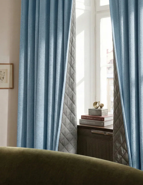 Rideaux sur mesure bleu en lin Kurtens encadrant une fenêtre, salon lumineux élégant