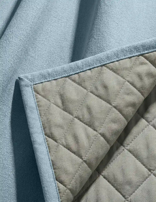 Gros plan sur le coin du rideau bleu Kurtens révélant la doublure matelassée beige en piqué losange thermique et phonique