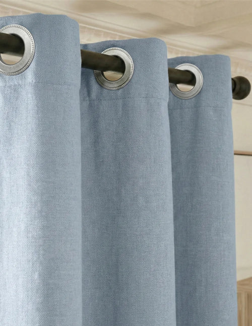Gros plan du rideau sur mesure bleu clair Kurtens avec œillets métalliques sur tringle noire, tissu doux à chiné subtil