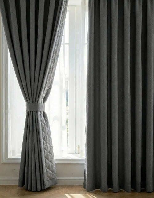 Paire de rideaux sur mesure gris anthracite Kurtens devant une fenêtre avec embrasse, révélant la doublure matelassée thermique phonique