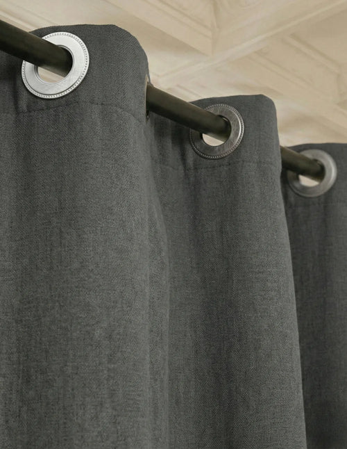 Rideau sur mesure gris anthracite Kurtens en gros plan avec œillets sur tringle noire, tissu épais isolant.