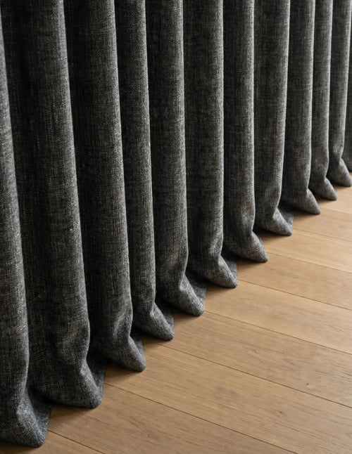 Détail du tombé du rideau occultant gris anthracite cassant sur le parquet