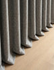 Détail du tombé du rideau occultant gris chiné cassant sur le parquet