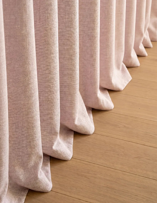 Détail du tombé du rideau occultant rose cassant sur le parquet