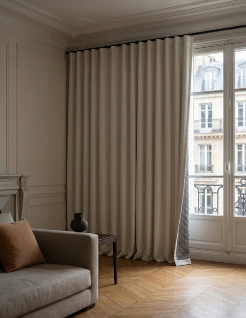 Rideau anti-bruit blanc cassé pleine hauteur dans un intérieur lumineux