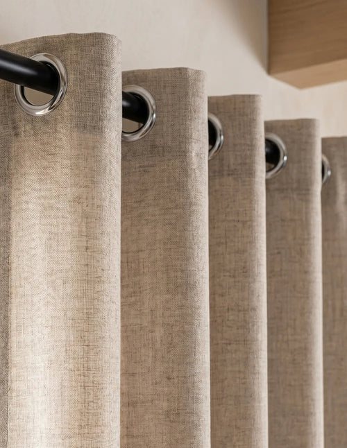 Détail du bas du rideau tamisant beige effet lin, plis ondulés laissant filtrer la lumière