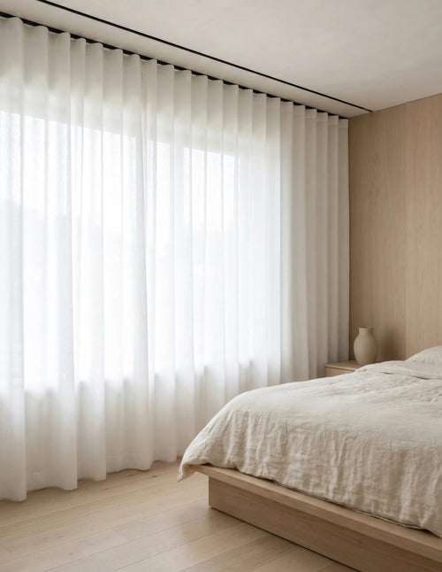 Rideau tamisant blanc effet lin diffusant la lumière du jour dans une chambre lumineuse