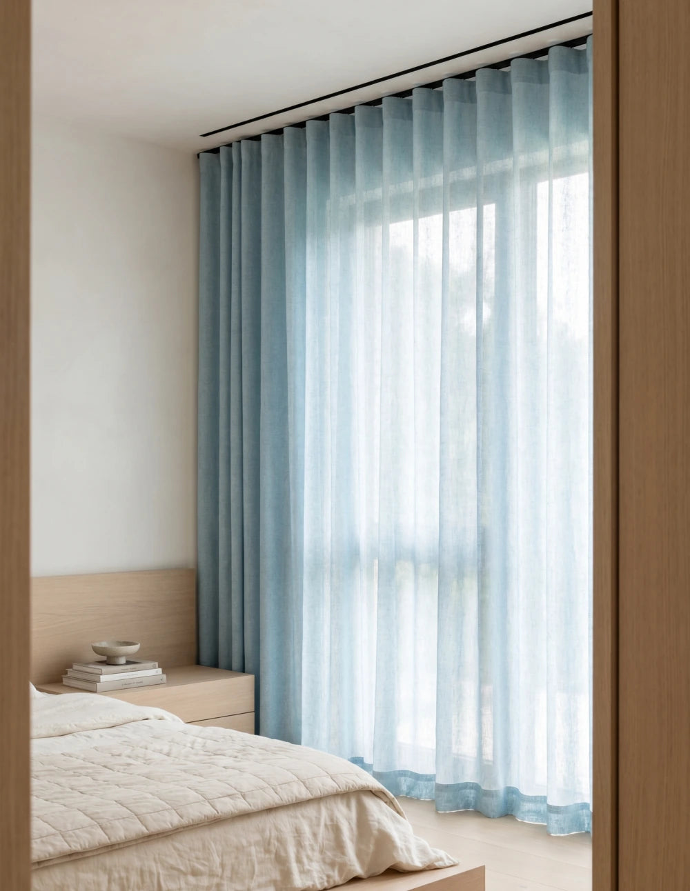 Tissu du rideau tamisant bleu effet lin drapé sur une chaise en bois, lumière du jour traversant la trame