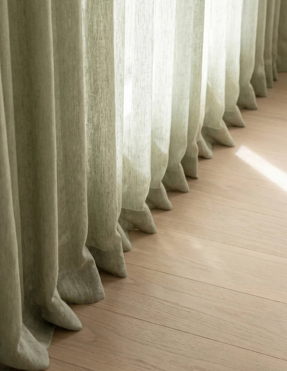 Détail du bas du rideau tamisant vert effet lin, plis ondulés laissant filtrer la lumière