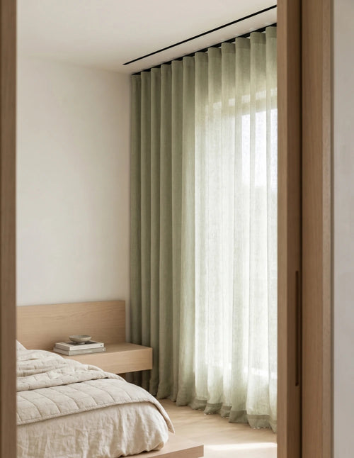 Tissu du rideau tamisant vert effet lin drapé sur une chaise en bois, lumière du jour traversant la trame