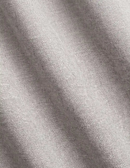 Rideau tamisant gris mauve effet lin tiré pleine hauteur devant une fenêtre dans une chambre claire en bois