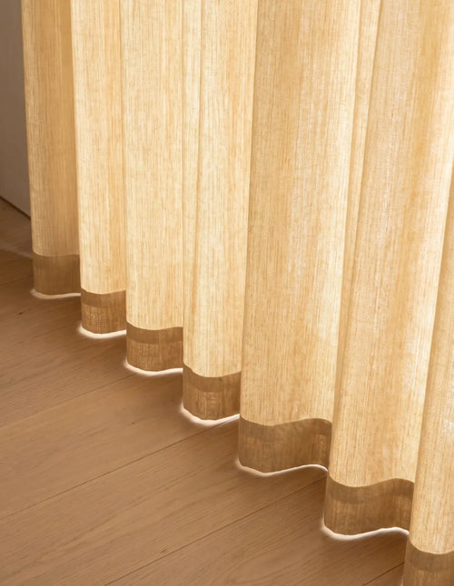 Détail du bas du rideau tamisant sable effet lin, plis ondulés laissant filtrer la lumière