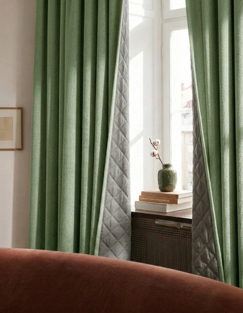 Rideaux sur mesure vert sauge Kurtens avec doublure matelassée visible, salon chaleureux avec canapé terracotta, céladon et cannage