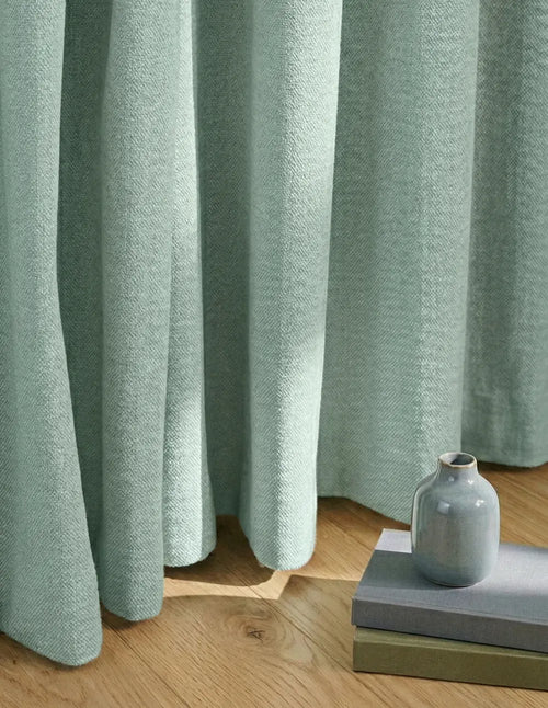 Rideau sur mesure vert menthe Kurtens tombé au sol, décoration épurée avec vase céramique. Occultant thermique et phonique.