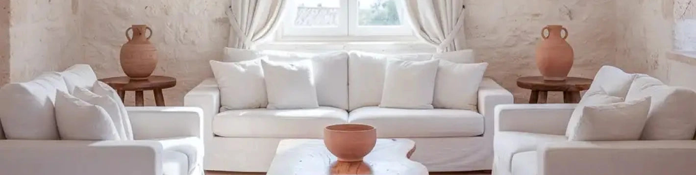 Bannière rideaux sur mesure crème Kurtens dans un salon méditerranéen épuré avec canapés blancs et poteries