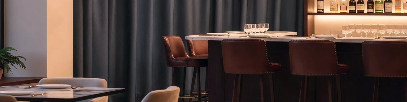 Bannière rideaux sur mesure gris Kurtens dans un bar gastronomique avec tabourets cuir, isolation acoustique