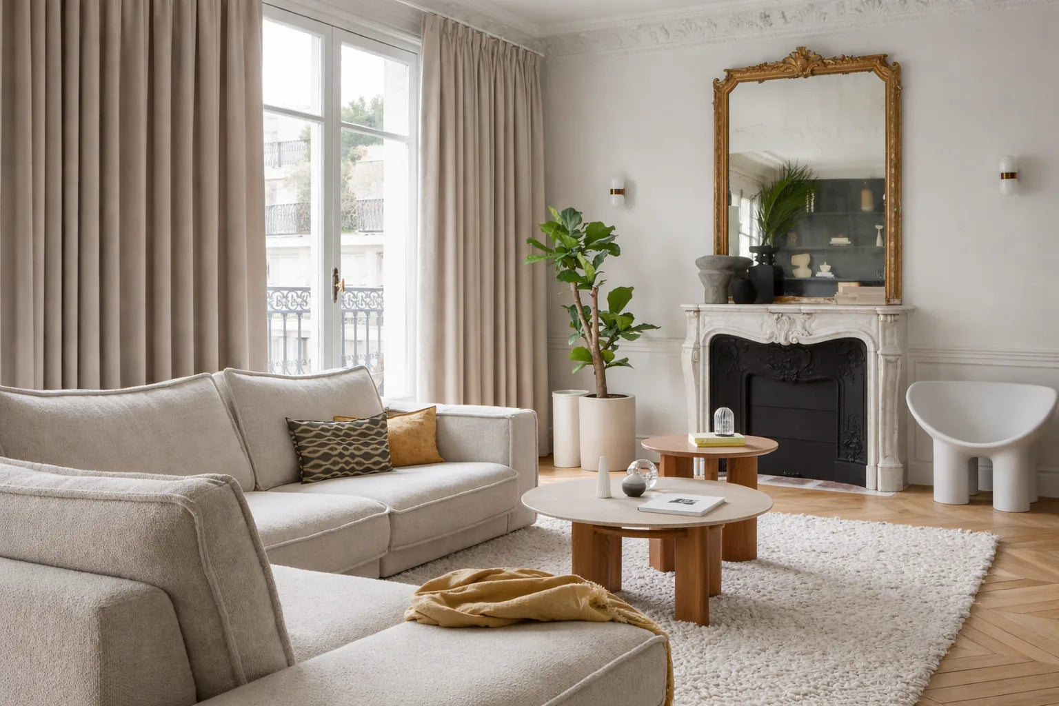 Salon haussmannien avec rideaux sur mesure Kurtens beige occultants thermiques phoniques, cheminée en marbre miroir doré, canapé bouclé crème, fauteuil sculptural et parquet point de Hongrie
