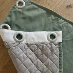 Avis client Kurtens : coin de rideau sur mesure vert sauge occultant thermique phonique avec œillets métalliques et doublure matelassée blanche en piqué losange sur parquet